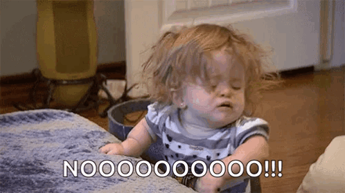 A Baby Girl Is Sitting On A Couch With Her Eyes Closed And Making A Face . GIF