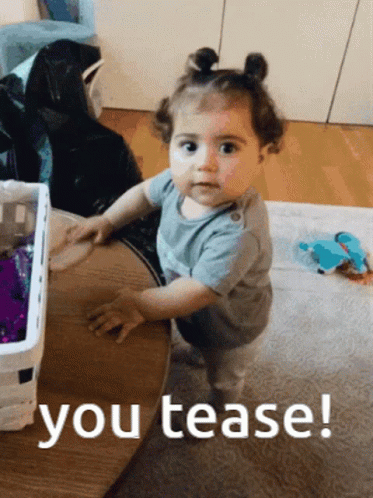 A Baby Girl Standing Next To A Table With The Words You Tease Written On The Bottom GIF