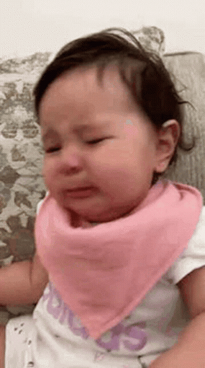 A Baby Girl Wearing A Pink Bandana Is Crying . GIF