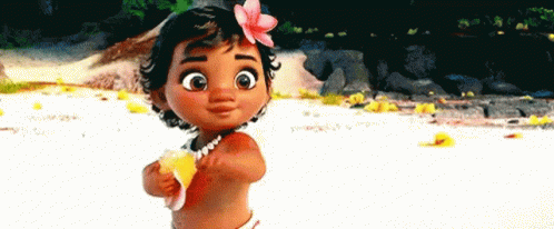A Baby Girl With A Flower In Her Hair Is Standing On A Beach Holding A Shell . GIF