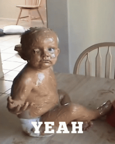 A Baby In A Diaper Is Sitting At A Table With The Word Yeah Written On The Bottom GIF