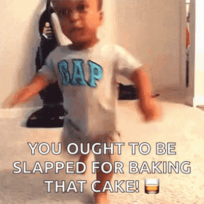 A Baby In A Gap Shirt Is Walking On A Carpet With A Glass Of Whiskey . GIF