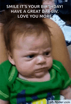 A Baby In A Green Shirt Is Making A Funny Face While Being Held By A Woman . GIF