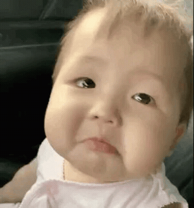A Baby In A Pink Dress Is Making A Sad Face . GIF