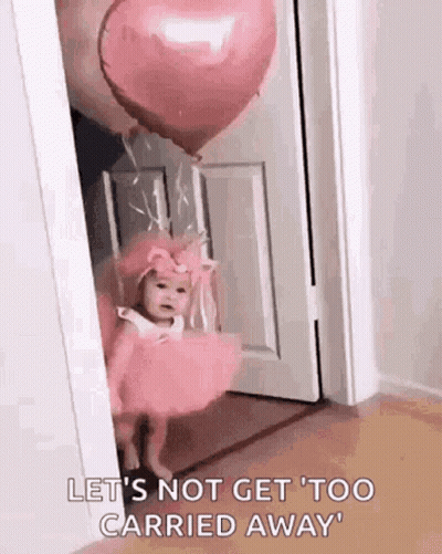 A Baby In A Pink Dress Is Standing In A Doorway With A Heart Shaped Balloon . GIF