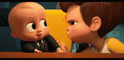 A Baby In A Suit And Tie Is Standing Next To A Boy In A Yellow Shirt And Talking To Him . GIF