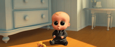 A Baby In A Suit And Tie Sits On The Floor Next To A Teddy Bear GIF