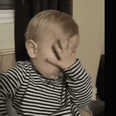 A Baby Is Covering His Face With His Hand . GIF