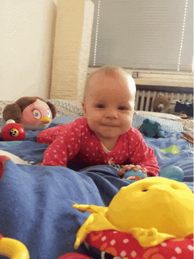 A Baby Is Crawling On A Bed With Toys GIF
