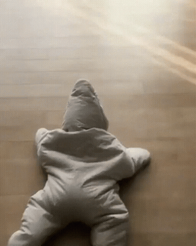 A Baby Is Crawling On The Floor Wearing A Star Shaped Outfit . GIF