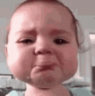A Baby Is Crying And Making A Funny Face While Looking At The Camera . GIF