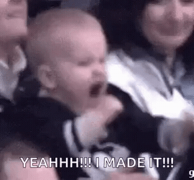 A Baby Is Crying In A Crowd Of People And A Woman Is Holding It . GIF