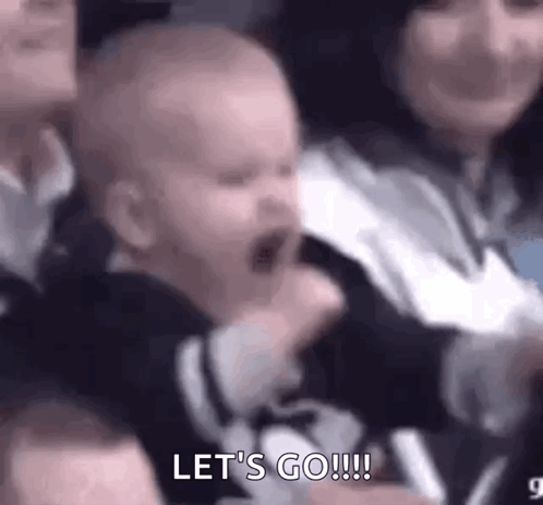 A Baby Is Crying In A Crowd Of People While A Woman Holds It In Her Arms . GIF