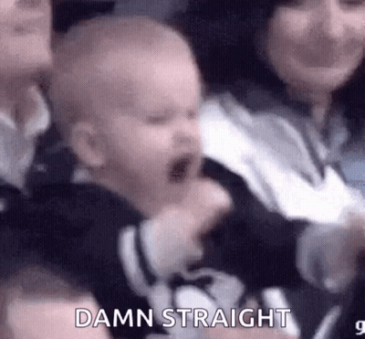 A Baby Is Crying In A Crowd Of People While A Woman Holds It . GIF