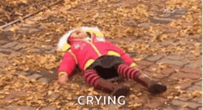A Baby Is Crying While Laying On The Ground With Leaves . GIF