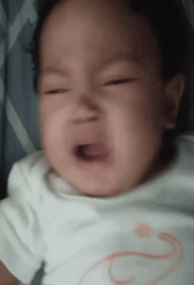 A Baby Is Crying With His Mouth Open And A White Shirt On . GIF