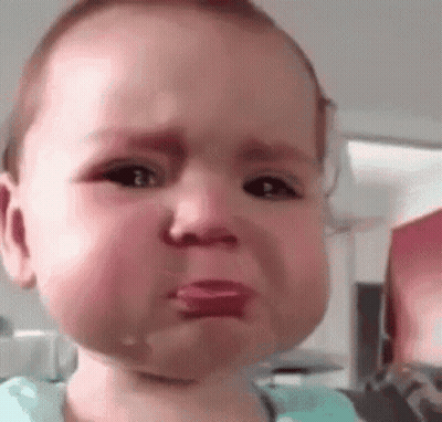 A Baby Is Crying With Tears Coming Out Of His Eyes And His Tongue Sticking Out . GIF