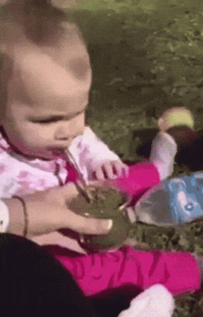A Baby Is Drinking From A Cup With A Spoon GIF