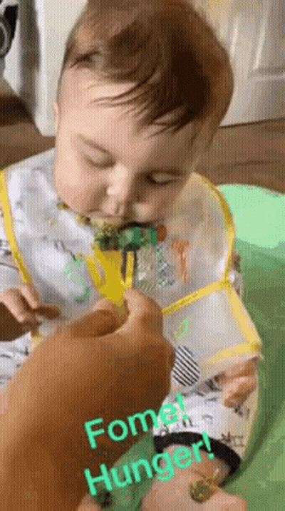 A Baby Is Eating Broccoli With A Fork And Bib On . GIF