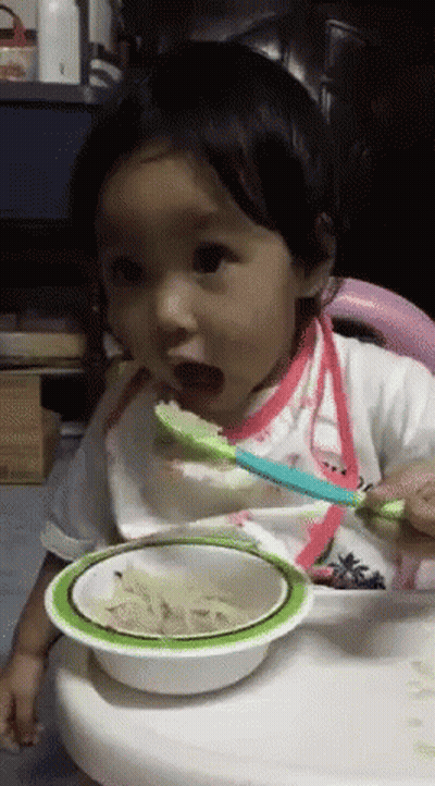 A Baby Is Eating From A Bowl With A Spoon In It GIF