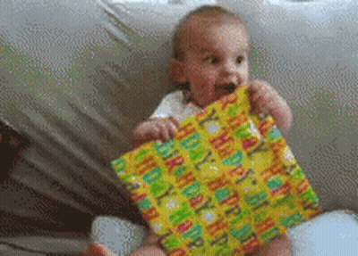 A Baby Is Holding A Happy Birthday Wrapped Present GIF