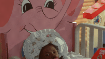 A Baby Is Laying In A Crib With A Pacifier In His Mouth And A Fire Helmet On The Bed GIF