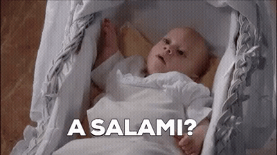 A Baby Is Laying In A Crib With The Words `` A Salami '' Written On The Bottom . GIF