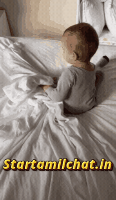 A Baby Is Laying On A Bed With The Website Starttamilchat.in Displayed GIF