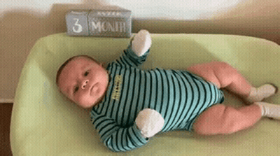 A Baby Is Laying On A Changing Table Next To A Sign That Says 3 Months . GIF