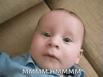A Baby Is Laying On A Couch And Making A Funny Face While Looking At The Camera . GIF