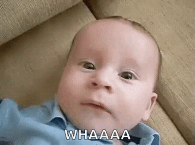A Baby Is Laying On A Couch And Making A Funny Face While Looking At The Camera . GIF