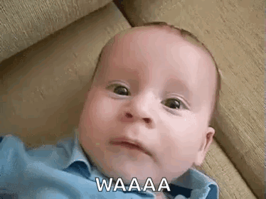 A Baby Is Laying On A Couch And Making A Funny Face While Looking At The Camera . GIF