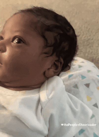 A Baby Is Laying On A Pillow With #Thepeoplescheerleader Written Below It GIF