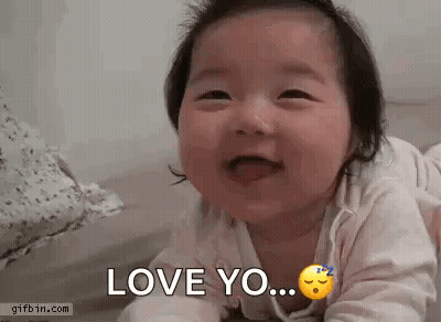 A Baby Is Laying On Its Stomach And Smiling While Saying `` Love You '' . GIF