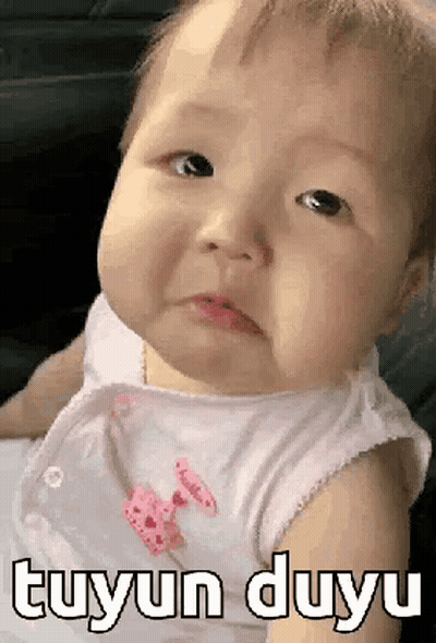 A Baby Is Making A Funny Face And The Baby Is Wearing A White Shirt . GIF