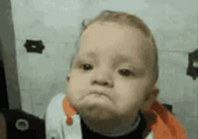 A Baby Is Making A Funny Face In Front Of A Wall . GIF