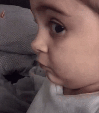 A Baby Is Making A Funny Face While Looking At The Camera . GIF