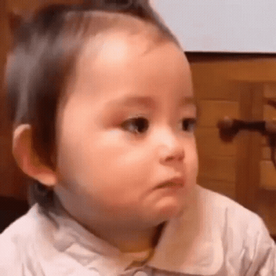 A Baby Is Making A Funny Face While Sitting Down . GIF
