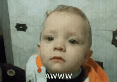 A Baby Is Making A Funny Face With The Words Awww Written Next To Him . GIF