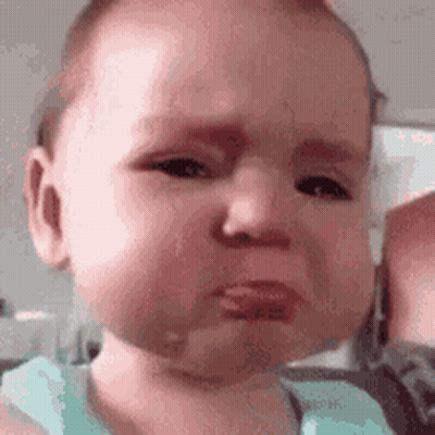 A Baby Is Making A Sad Face While Being Held By A Person . GIF