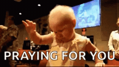 A Baby Is Praying For You While Sitting At A Table In A Church . GIF