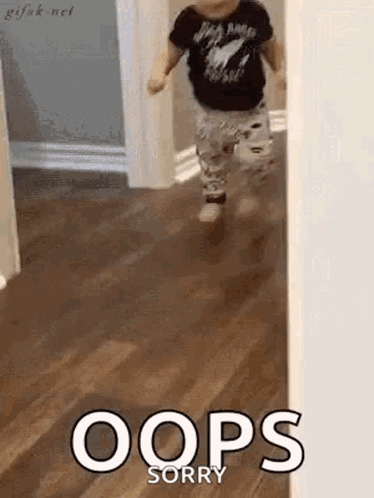 A Baby Is Running Down A Hallway With The Words Oops Sorry Written On The Floor . GIF