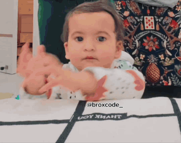 A Baby Is Sitting At A Table With A Blanket That Says Broxcode_ On It GIF