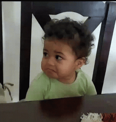 A Baby Is Sitting At A Table With A Sad Look On His Face GIF