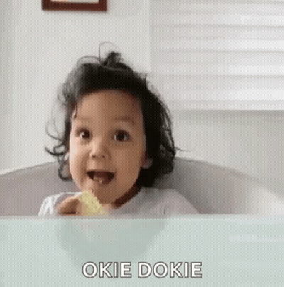 A Baby Is Sitting In A Bathtub Eating A Cookie And Making A Funny Face . GIF