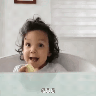 A Baby Is Sitting In A Bathtub With A Cookie In His Mouth And The Words Gog On The Bottom . GIF