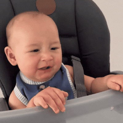 A Baby Is Sitting In A High Chair And Looking At Something GIF