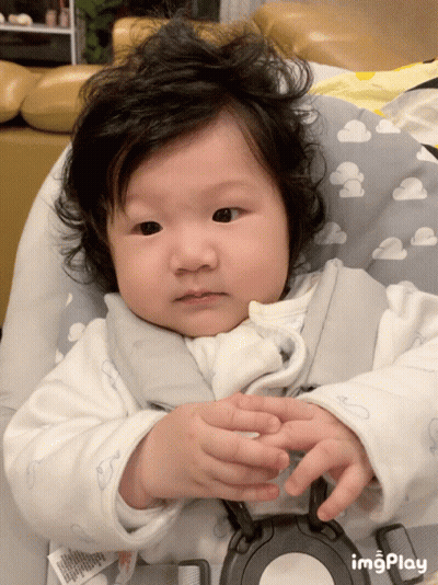 A Baby Is Sitting In A High Chair With A Cloudy Pillow GIF