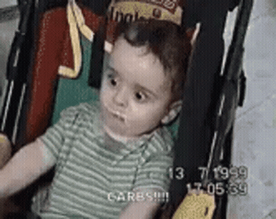 A Baby Is Sitting In A Stroller With A Crown On His Head . GIF