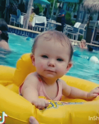 A Baby Is Sitting In A Yellow Float In A Pool GIF